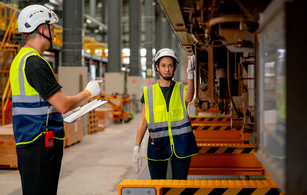Szakmai mérnök vagy technikus nő ellenőrizze és vitassa meg a problémát alkatrészek elektromos vonat alatt a munkatárs férfi munkahelyi területen. - Fotó, kép