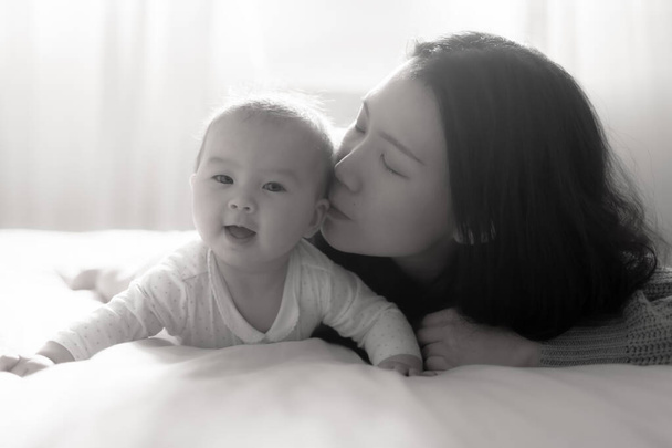love and playfulness, a young Asian Korean woman joyfully engages with her baby girl on the bed. Their laughter creates precious memories together bonding in pure happiness - Foto, immagini