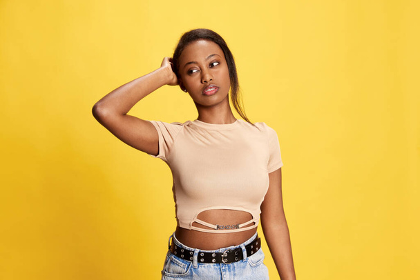 Portrait of young, beautiful african girl in casual clothes posing against yellow studio background. Concept of lifestyle, human emotions, fashion, beauty, facial expression, ad - Fotografie, Obrázek