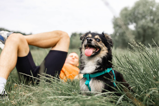 szczęśliwy przyjaciele człowiek i pies Labrador siedzi na trawie w letnim parku.  - Zdjęcie, obraz
