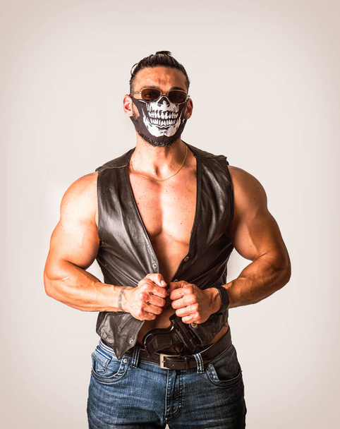 Handsome muscular man with mask over face as a robber or bandit in studio shot - Foto, Bild