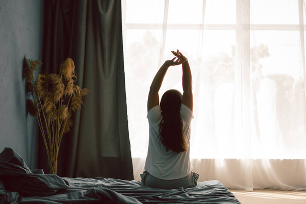 Les jeunes femmes se réveillent le matin, s'étirent le week-end sur le lit. Concept relax et week-end. Espace de copie - Photo, image