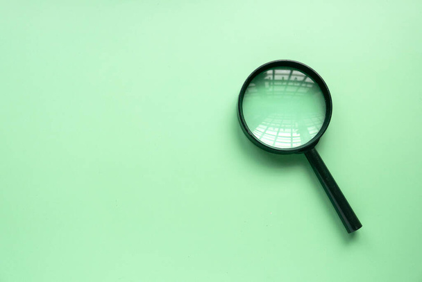 Magnifying glass over a green background. Copy space. - Фото, зображення