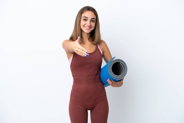 Young sport caucasian woman going to yoga classes isolated on white background shaking hands for closing a good deal - Foto, Bild