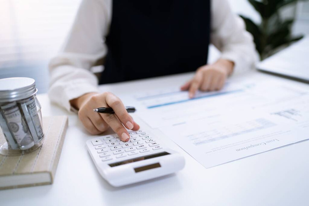 Businesswoman Accountant analyzing investment charts Invoice and pressing calculator buttons over documents. Accounting Bookkeeper Clerk Bank Advisor And Auditor Concept. - Photo, Image