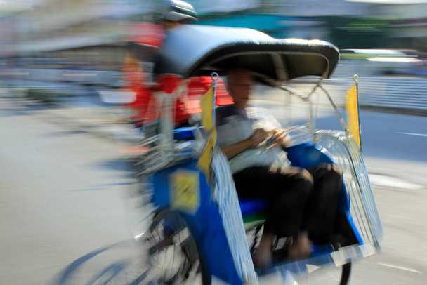 Θολή εικόνα, παραδοσιακό rickshaw βόλτες γρήγορα και δίνει ένα κινούμενο αποτέλεσμα. - Φωτογραφία, εικόνα