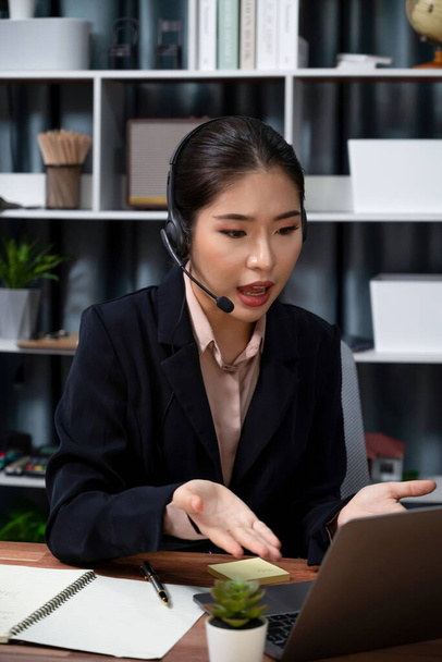 Asiatisches Callcenter mit Headset und Mikrofon an ihrem Laptop. Betreiberinnen bieten einen außergewöhnlichen Kundenservice. Supportive Call Center Agent hilft Kunden auf Anfrage. Enthusiastisch - Foto, Bild