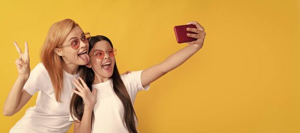 Mother and daughter child banner, copy space, isolated background. funny mom and kid making selfie on smartphone, portrait - Foto, afbeelding
