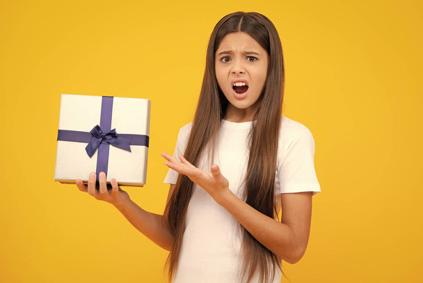 Portrait of teenager child girl 12, 13, 14, years old holding Christmas gift box. Teen giving birthday gift. Angry face, upset emotions of teenager girl - Φωτογραφία, εικόνα