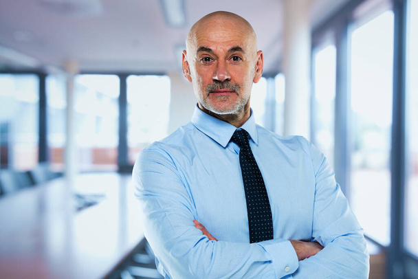 Portrait of mid aged professional man wearing shirt and tie and standing at the conference room. - Foto, afbeelding