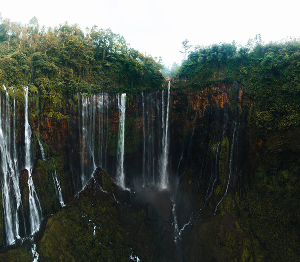View from above, stunning aerial view of the Tumpak Sewu Waterfalls also known as Coban Sewu with the Semeru volcano in the distance, Malang Regency,East Java, Indonesia - 写真・画像