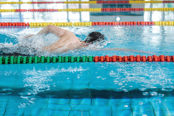 Professional male swimmer swimming the front crawl style. Freestyle competition concept. - Foto, afbeelding