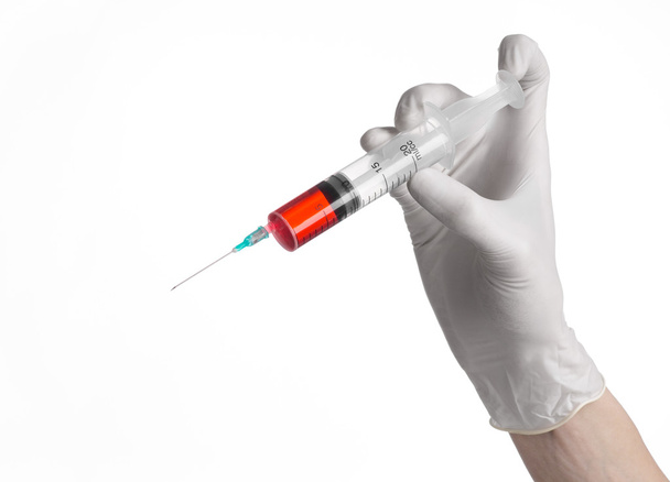 Doctor's hand holding a syringe, white-gloved hand, a large syringe, medical issue, the doctor makes an injection, white background, isolated, white gloves doctor, ebola test, red medication - Foto, Imagem