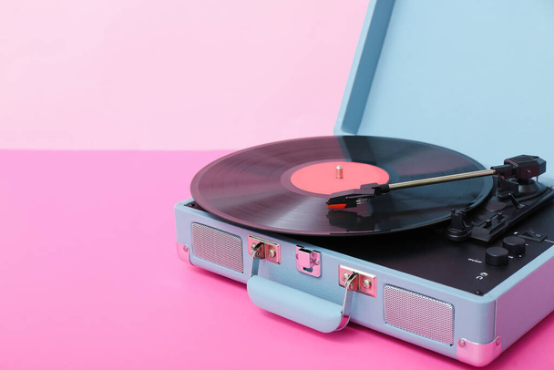 Record player with vinyl disk on table near pink wall, closeup - Photo, Image