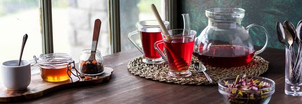 Верхняя сцена стола с чаем гибискус, подаваемым с медом, готовым к употреблению. - Фото, изображение