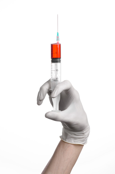 Doctor's hand holding a syringe, white-gloved hand, a large syringe, medical issue, the doctor makes an injection, white background, isolated, white gloves doctor, ebola test, red medication - Foto, immagini