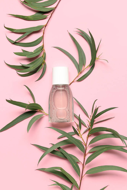 Bottle of micellar water with plant branches on pink background - Фото, зображення