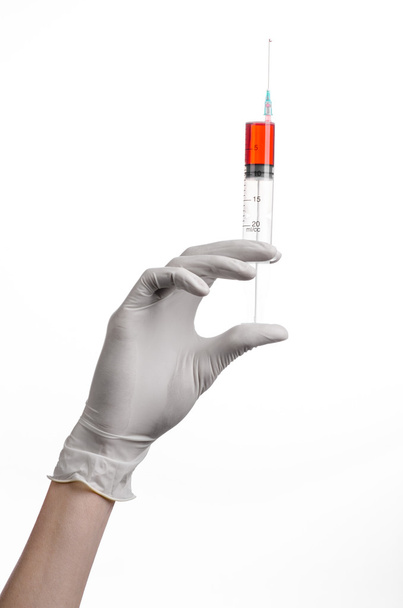 Doctor's hand holding a syringe, white-gloved hand, a large syringe, medical issue, the doctor makes an injection, white background, isolated, white gloves doctor, ebola test, red medication - Zdjęcie, obraz