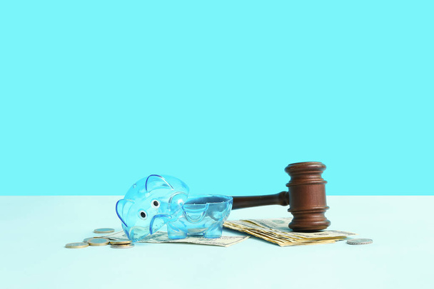 Broken plastic piggy bank with judge gavel and money on blue background. Bankruptcy concept - Fotó, kép