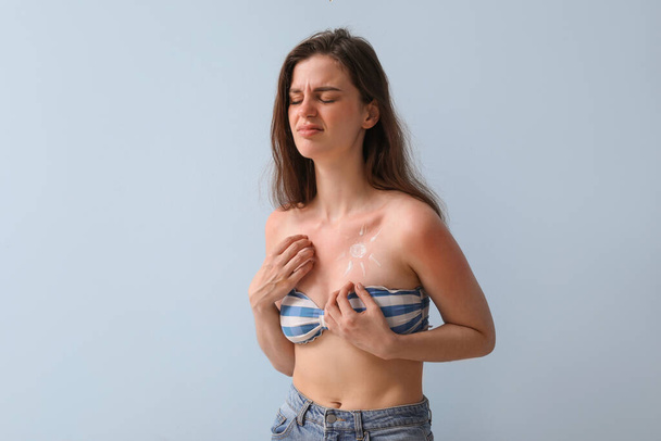Аллергия молодая женщина с обгорелой кожей и солнцем из крема на синем фоне - Фото, изображение