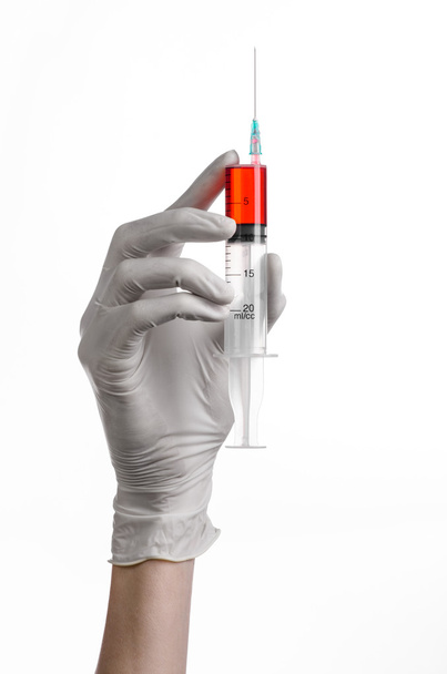 Doctor's hand holding a syringe, white-gloved hand, a large syringe, medical issue, the doctor makes an injection, white background, isolated, white gloves doctor, ebola test, red medication - Fotoğraf, Görsel