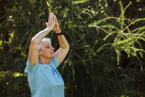 短髪ヨガや太極拳を屋外で練習しているシニア女性。老婦人瞑想. - 写真・画像