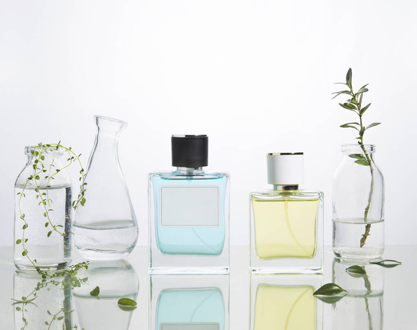 Parfümflaschen und Vasen mit frischen Zweigen und Blumen auf einem Glashintergrund. Freiraum für Text. - Foto, Bild