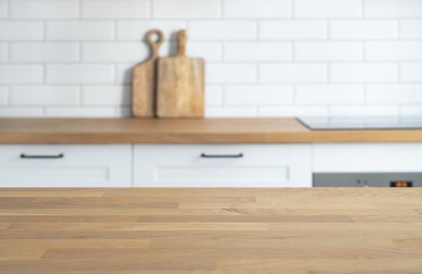 Wooden oak countertop with free space for mounting a product or layout against the background of a blurred white kitchen. Copy space - Foto, afbeelding