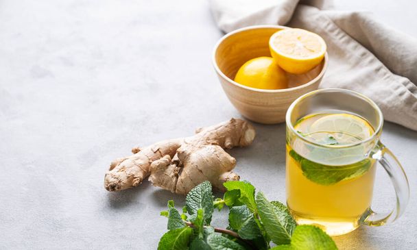 Aroma glass of tea with fresh lemon, mint and ginger on a light background with morning light. The concept of a healthy drink for immunity. Free space for text. - Foto, imagen