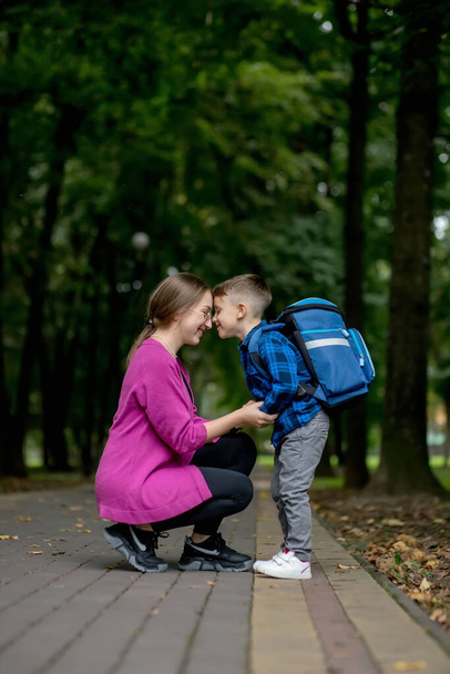 Young mother embraces her excited first class son on the way to school. Ready to study. - Valokuva, kuva