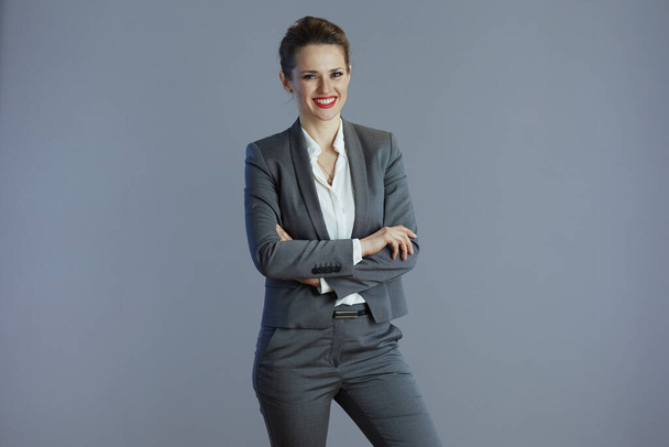 happy stylish middle aged small business owner woman in grey suit against gray background. - 写真・画像