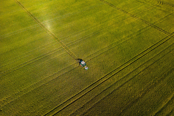 Um trator em um campo com grãos e várias faixas de trator em campo de grãos verdes, Alemanha - Foto, Imagem