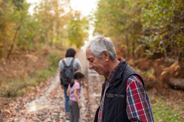 Ηλικιωμένος άνδρας με την εγγονή και την εγγονή του πεζοπορία στο φθινόπωρο δάσος - Φωτογραφία, εικόνα