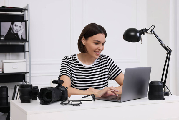 Young professional photographer with camera working on laptop in modern photo studio - Fotoğraf, Görsel