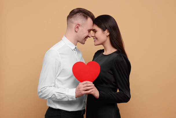 Lovely couple with decorative heart on beige background. Valentine's day celebration - 写真・画像