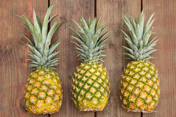 Delicious ripe pineapples on wooden table, flat lay - Fotografie, Obrázek