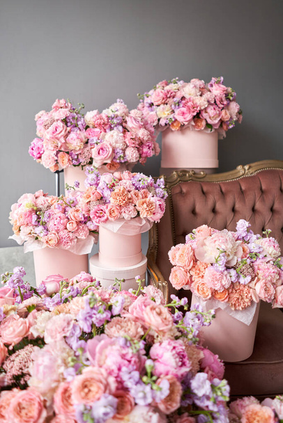 Ajándék doboz virágokkal egy gyönyörű belső térben, egy kanapé hátterében. Virágok, mint egy ajándék a szeretett nőnek. A virágos szoba. Egy doboz virág az Anyák Napjára. Kiváló minőségű fénykép - Fotó, kép