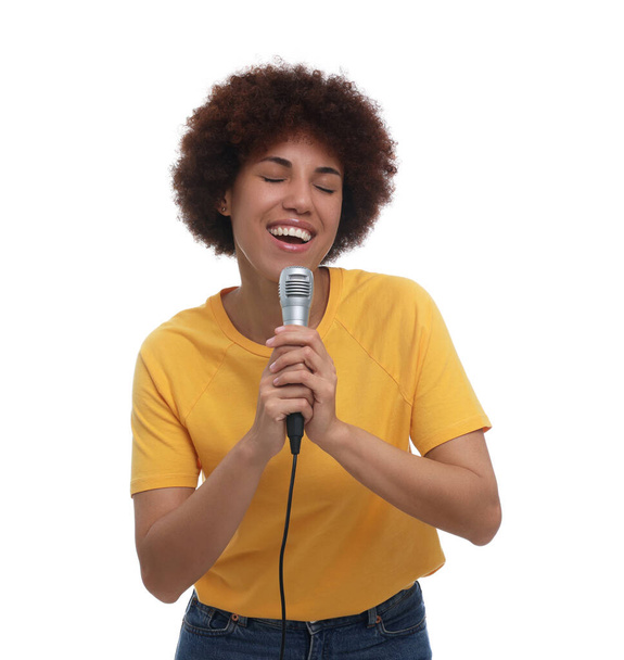 Curly young woman with microphone singing on white background - Valokuva, kuva