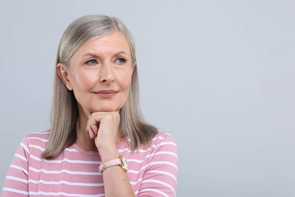 Portrait of beautiful senior woman on light grey background. Space for text - Zdjęcie, obraz