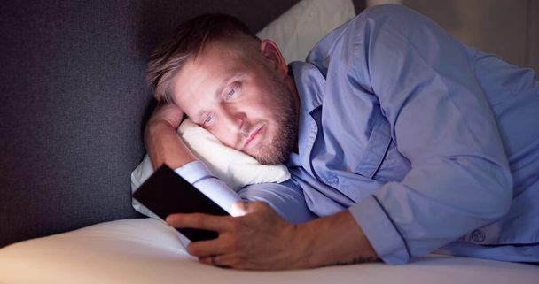 Man Lying On Bed Using Mobile Phone At Night - Valokuva, kuva