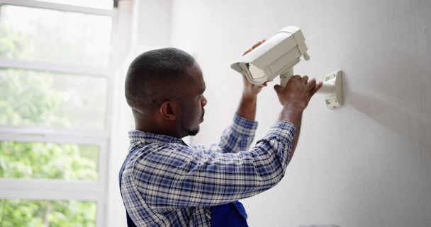 Close-up Of Technician Adjusting CCTV Camera On Wall - Foto, afbeelding