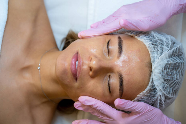 Face massage after skin care procedure in a beauty spa salon, cosmetologist, aesthetic clinic. - Фото, зображення