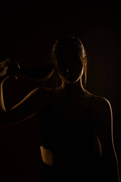An adorable girl posing while pulling her hair. She is wearing black bra - Fotó, kép