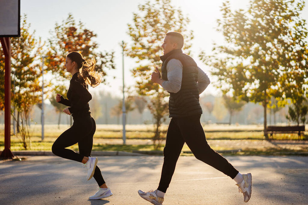 Jogging in the park. Handsome male and lovely female sports people warming up before training - Foto, imagen