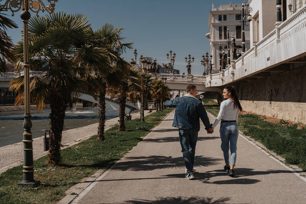 Beautiful couple walking while holding hands at the park in the city - Fotó, kép