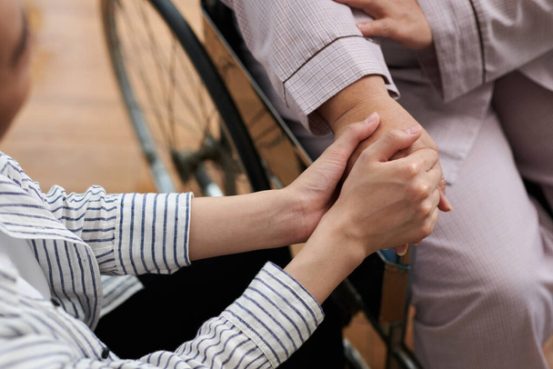 Смотритель держит за руку старшего пациента, чтобы поддержать ее - Фото, изображение