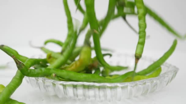Padající zelená chilli papričky ve skleněné misce - Záběry, video