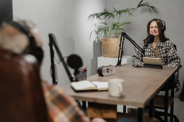 Um homem e uma mulher sentam-se à mesma mesa em frente aos microfones. Dois blogueiros estão gravando um podcast conjunto. Foto de alta qualidade - Foto, Imagem