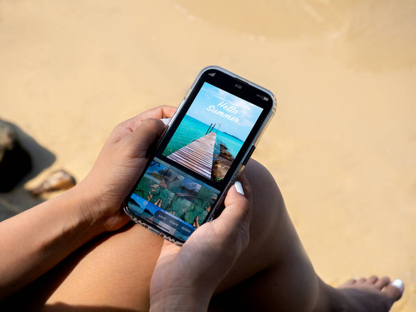 Edycja zdjęć z koncepcji smartfona komórkowego. Widok na morze edycja fotografii w aplikacji na ekranie smartfona w rękach kobiety, podróżować na plaży w lecie. Retuszowanie obrazów na portalach społecznościowych. - Zdjęcie, obraz