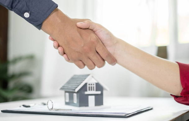 Üzletemberek és brókerek ingatlanügynökök kezet ráznak, miután befejezték a házvásárlásról szóló tárgyalásokat és aláírták a szerződéseket. Lakásbiztosítás fogalma. - Fotó, kép